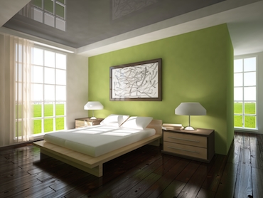room with a 
               hardwood floor, bright windows on two sides, and a two-person bed with a 
               bedside table and lamp on each side